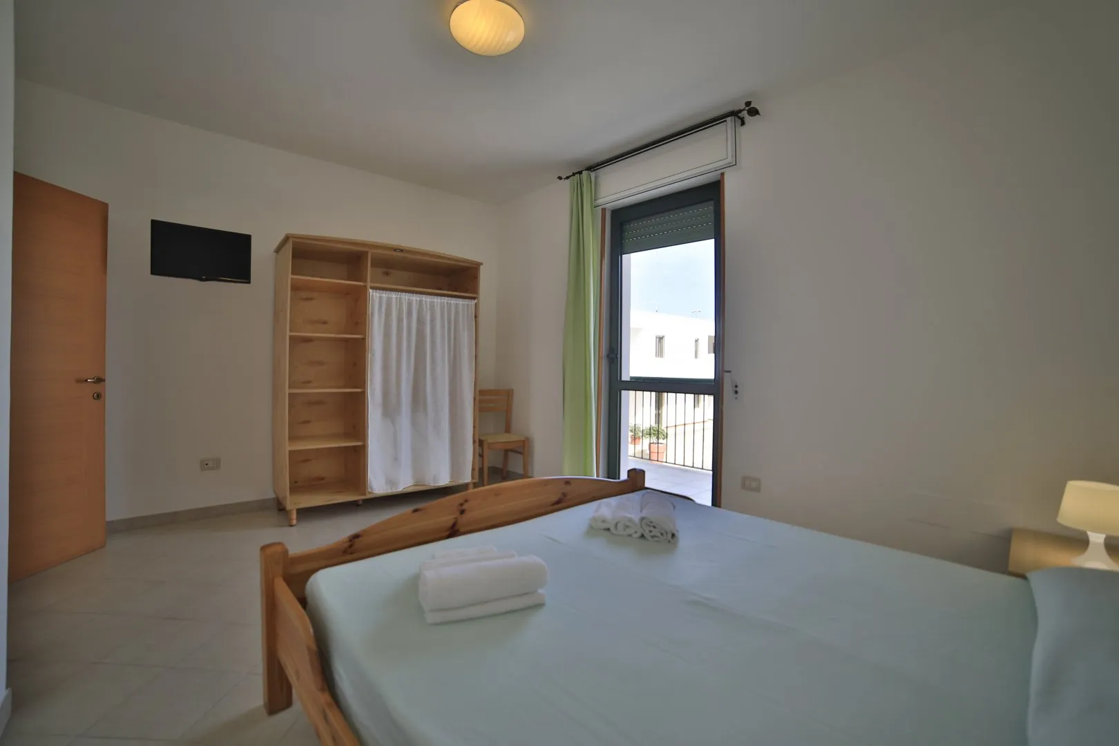 Camera da letto matrimoniale con armadio, TV e accesso al balcone
