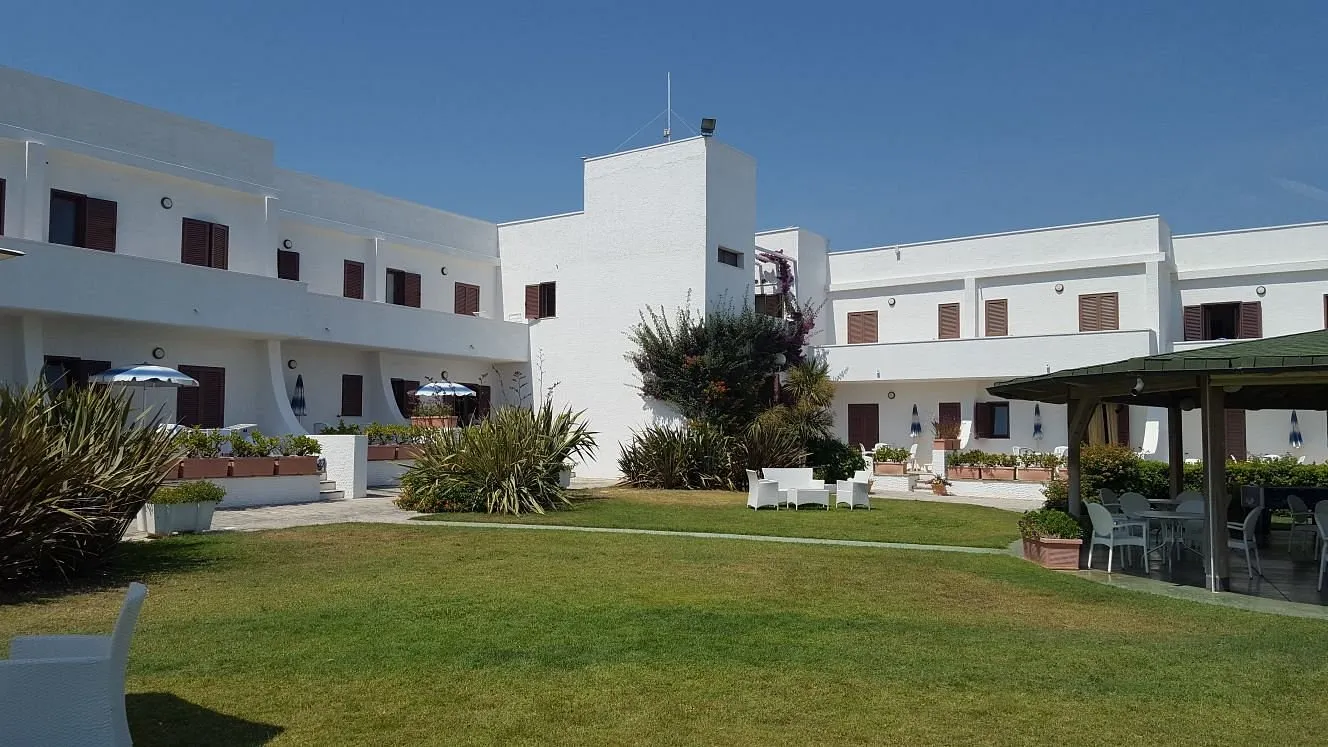 Cortile interno del residence con prato verde, poltrone bianche e gazebo per la ristorazione