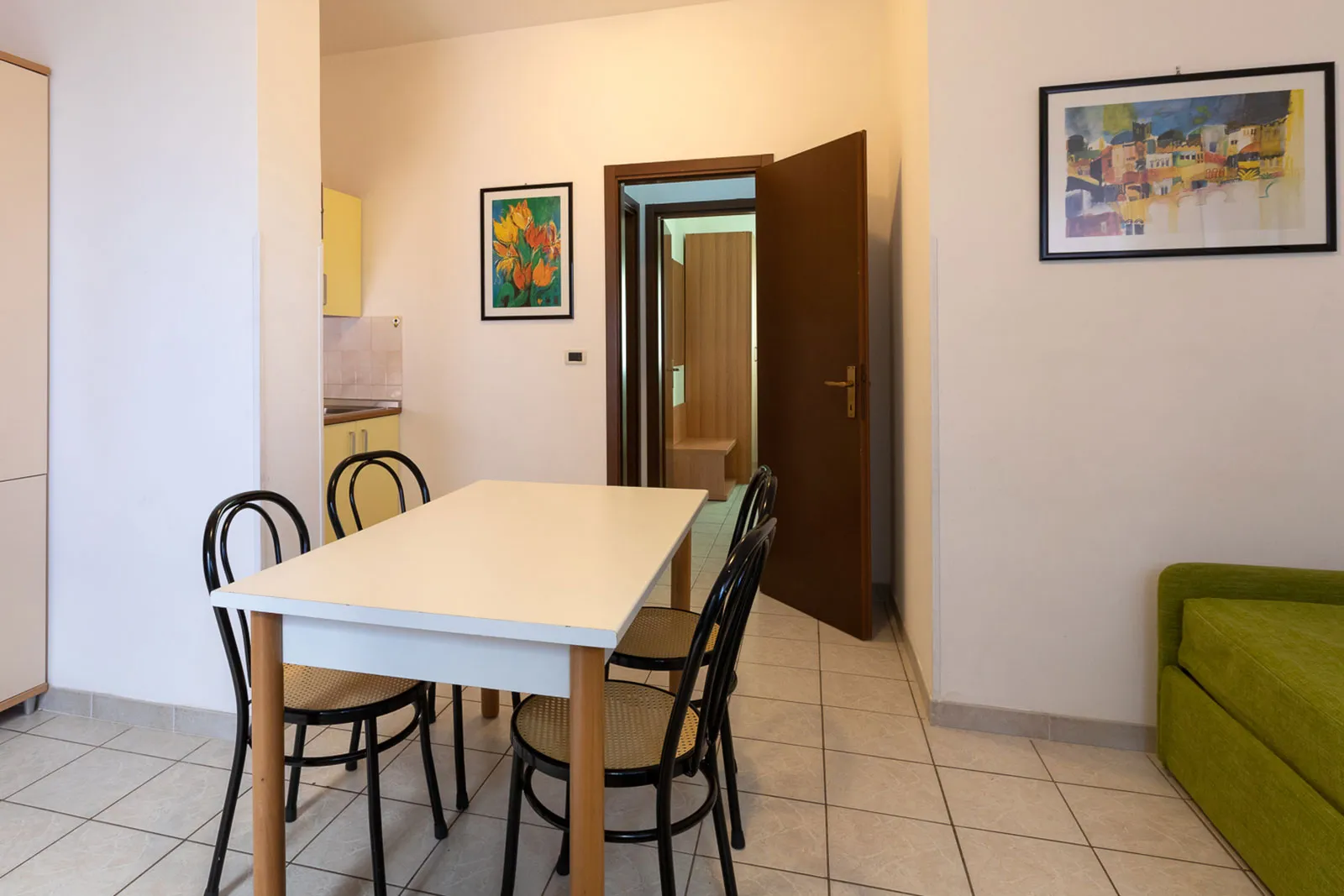 Zona pranzo dell'appartamento con tavolo, sedie e divano verde