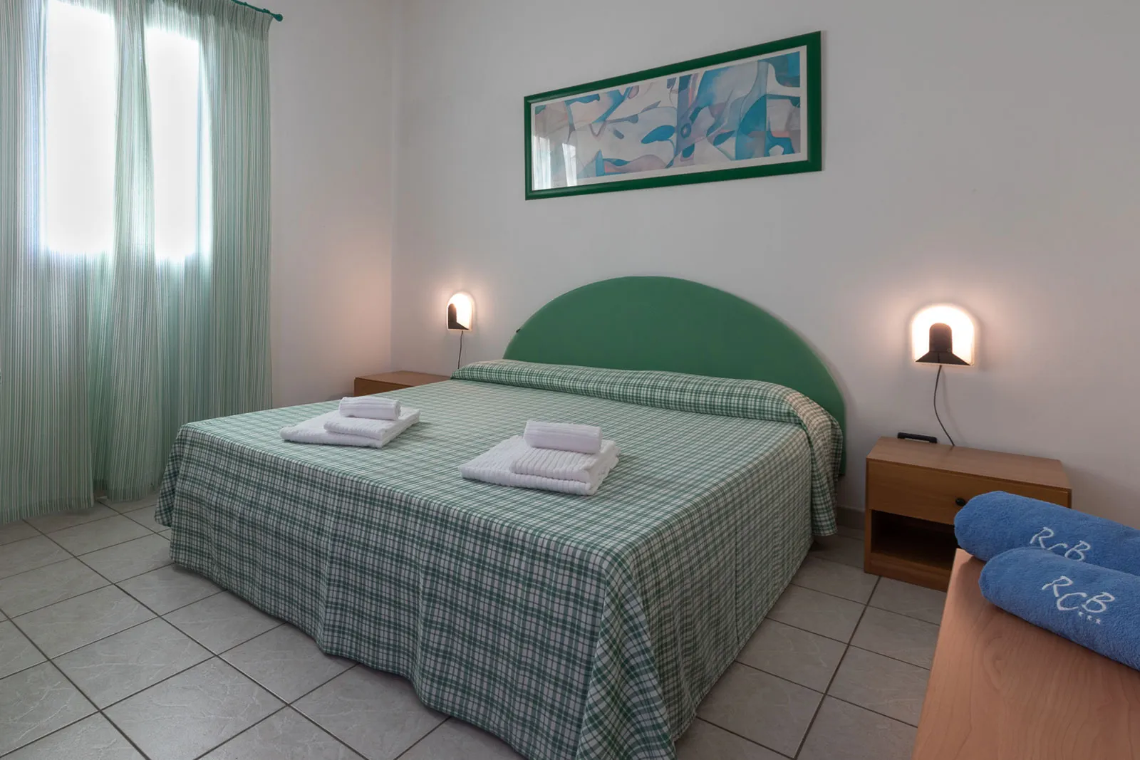 Camera da letto matrimoniale con testiera verde e copriletto a quadri