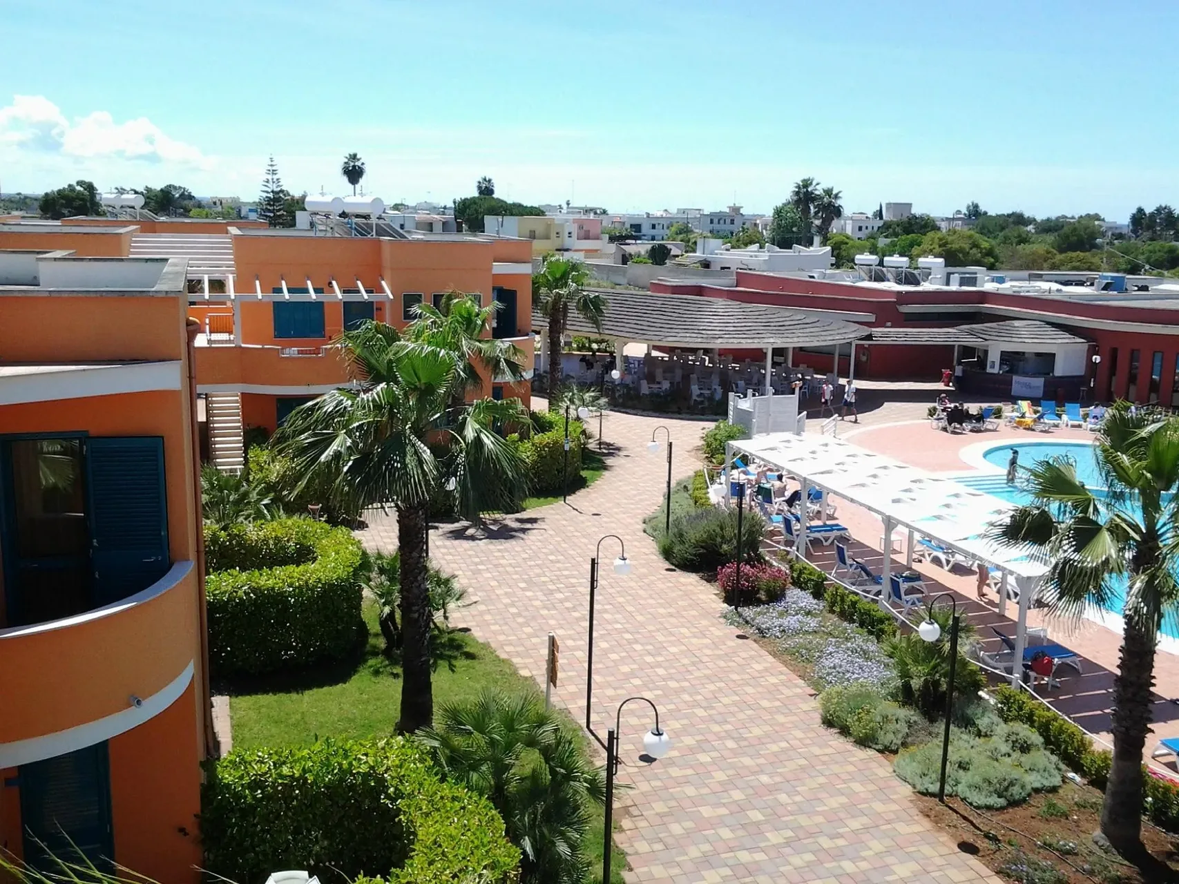 Vista panoramica del resort con residence color arancio, piscina e giardini curati