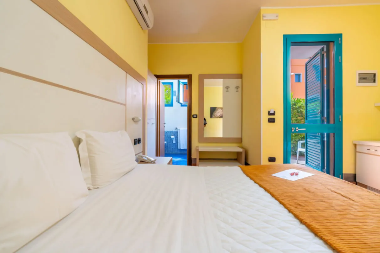 Camera con letto matrimoniale, accesso al bagno e porta-finestra sul giardino
