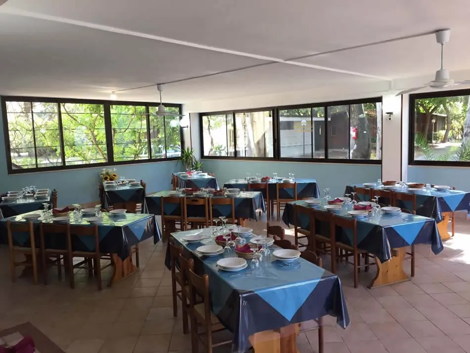Sala ristorante interna con tavoli apparecchiati e tovaglie blu