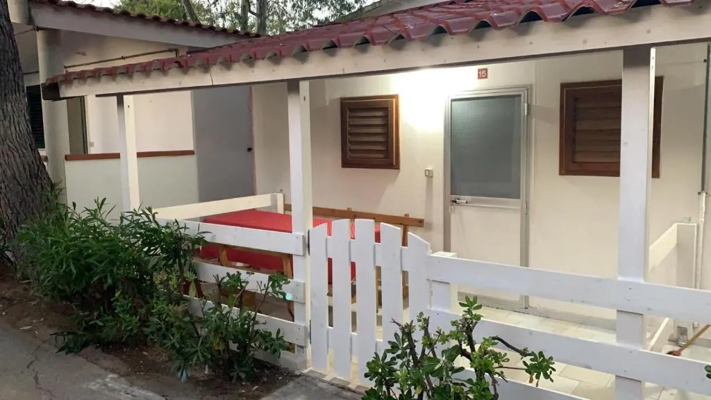 Ingresso di bungalow bianco con veranda e staccionata in legno