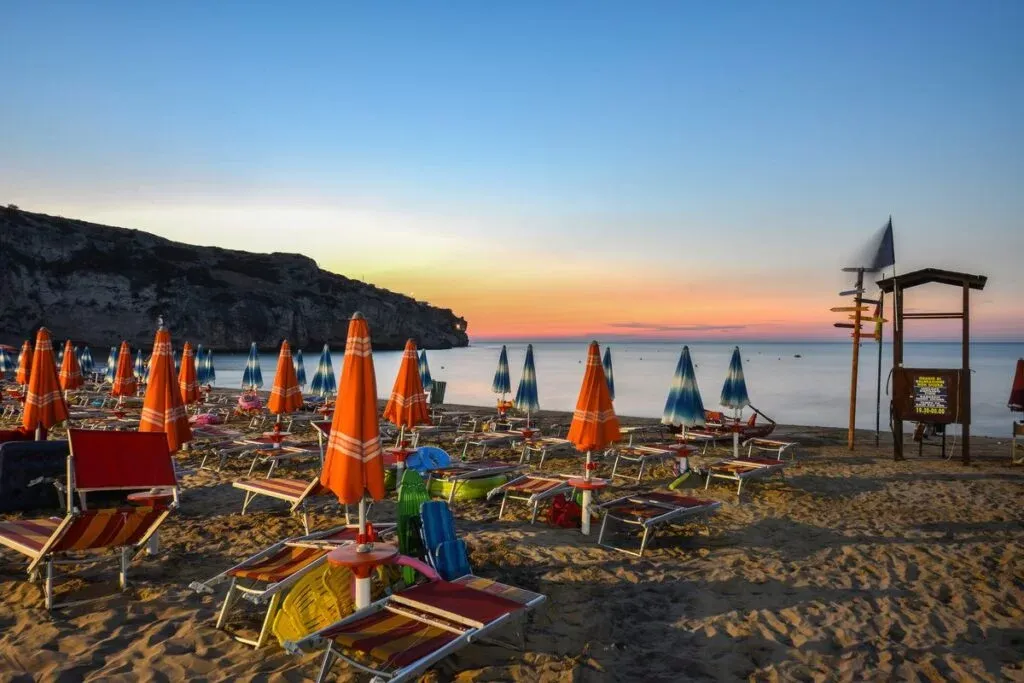 Spiaggia con ombrelloni e lettini al tramonto sul mare