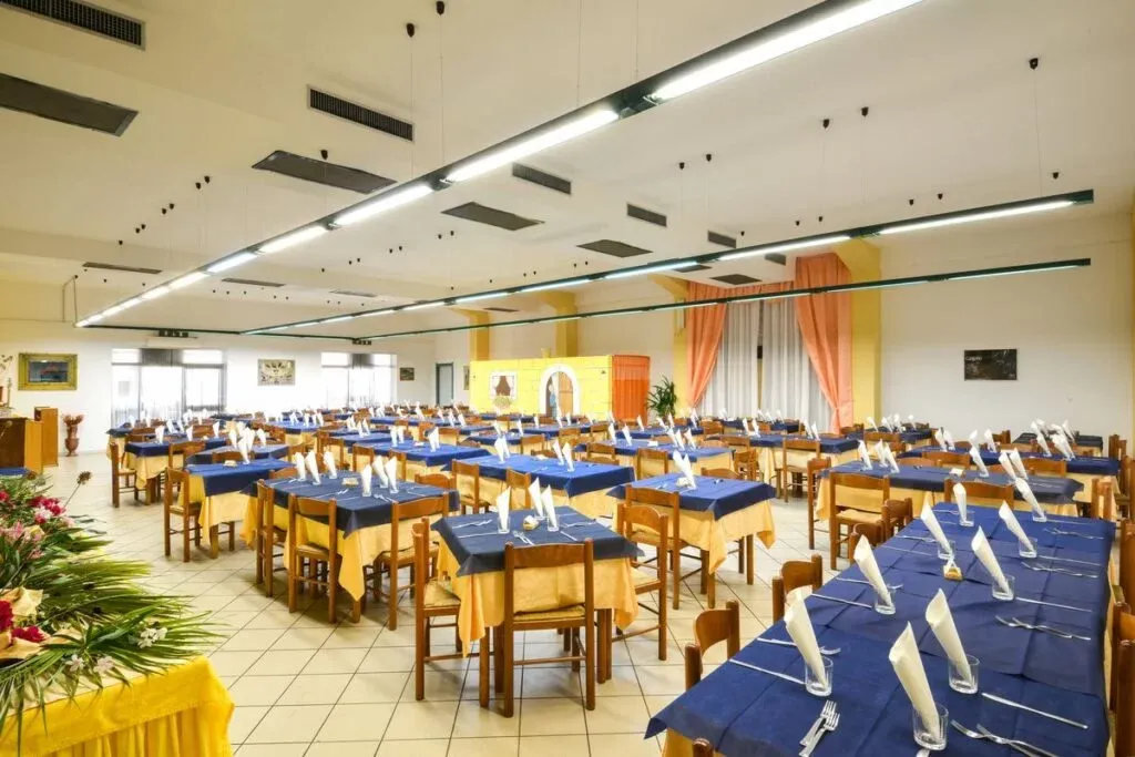 Sala ristorante con tavoli apparecchiati con tovaglie blu e gialle