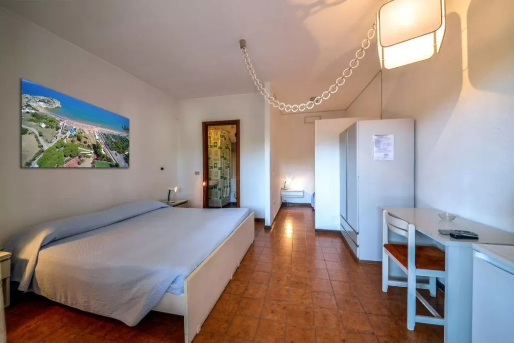 Camera da letto luminosa con letto, scrivania e bagno privato