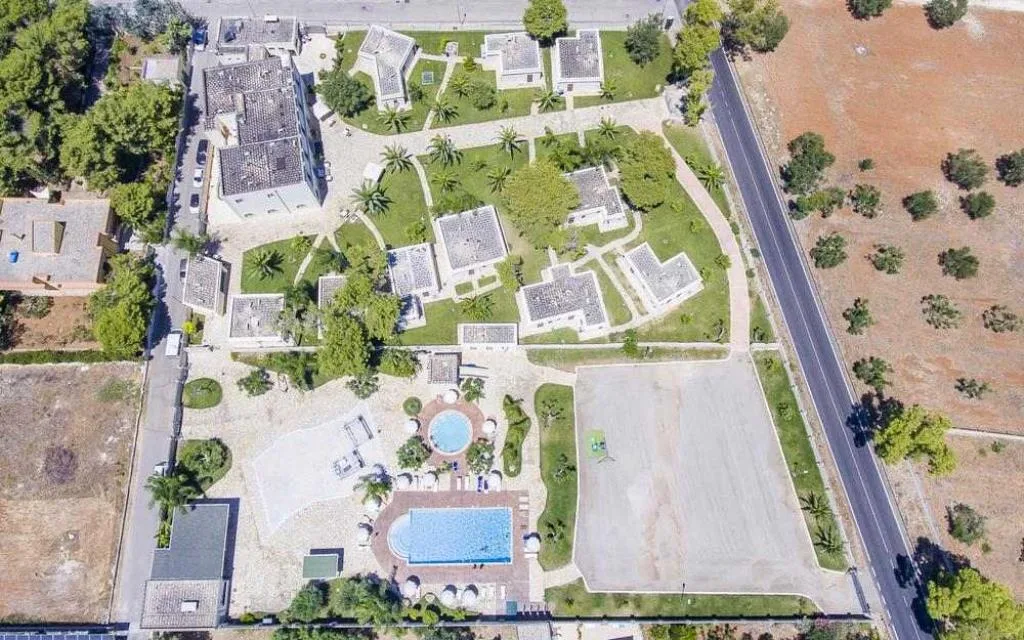 Veduta aerea della struttura con bungalow, giardino, palme e piscine