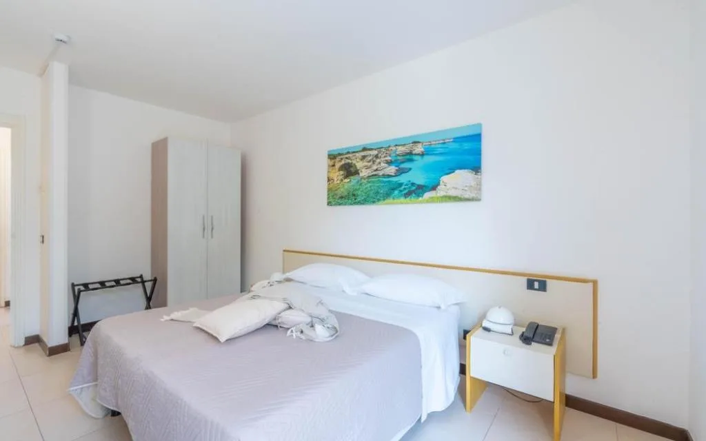 Camera luminosa con letto matrimoniale, armadio e quadro del mare