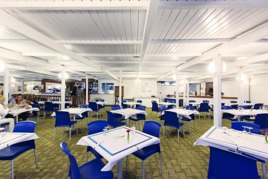 Sala ristorante interna con tavoli apparecchiati e sedie blu