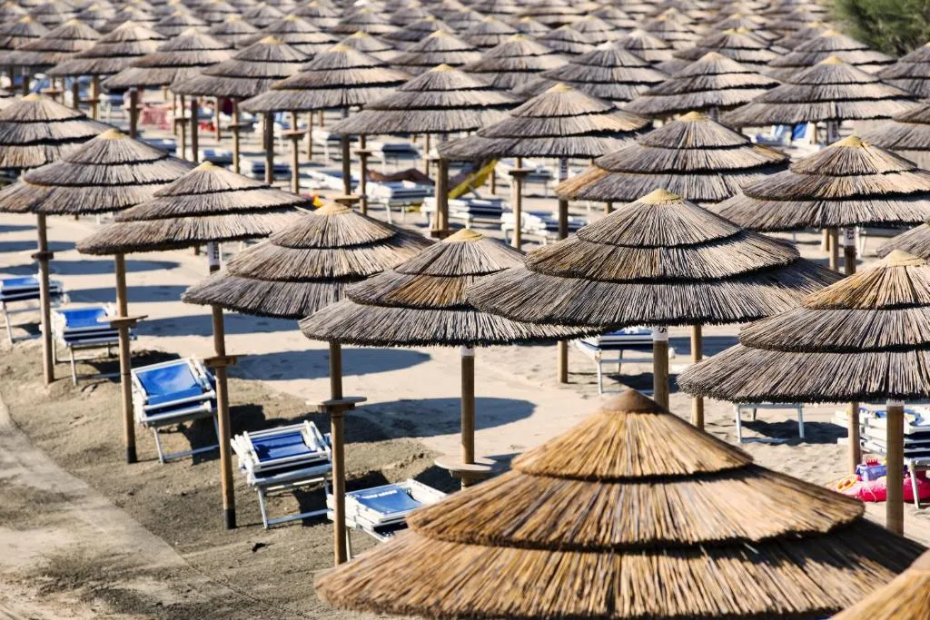 Dettaglio degli ombrelloni in paglia e lettini sulla spiaggia di sabbia