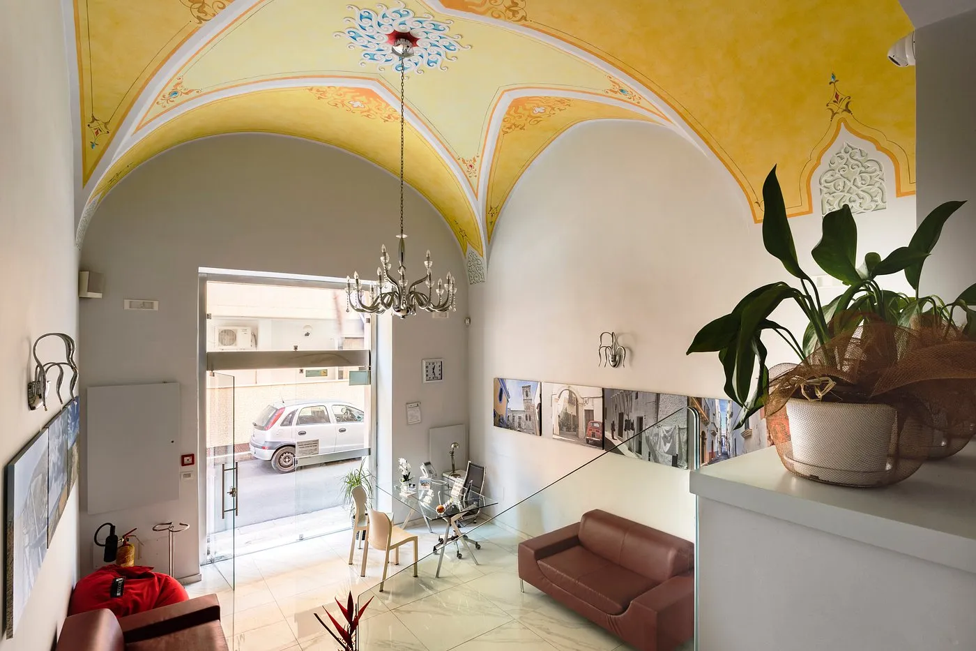 Hall con soffitto a volta affrescato giallo, lampadario di cristallo e divani in pelle