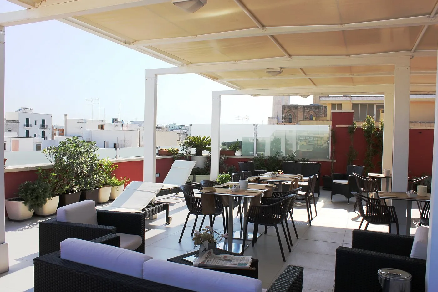 Terrazza con tavoli da pranzo, divani, lettino e vista sui tetti della città