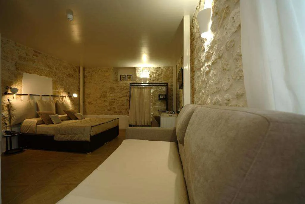 Camera con letto matrimoniale, divano e pareti in pietra illuminate
