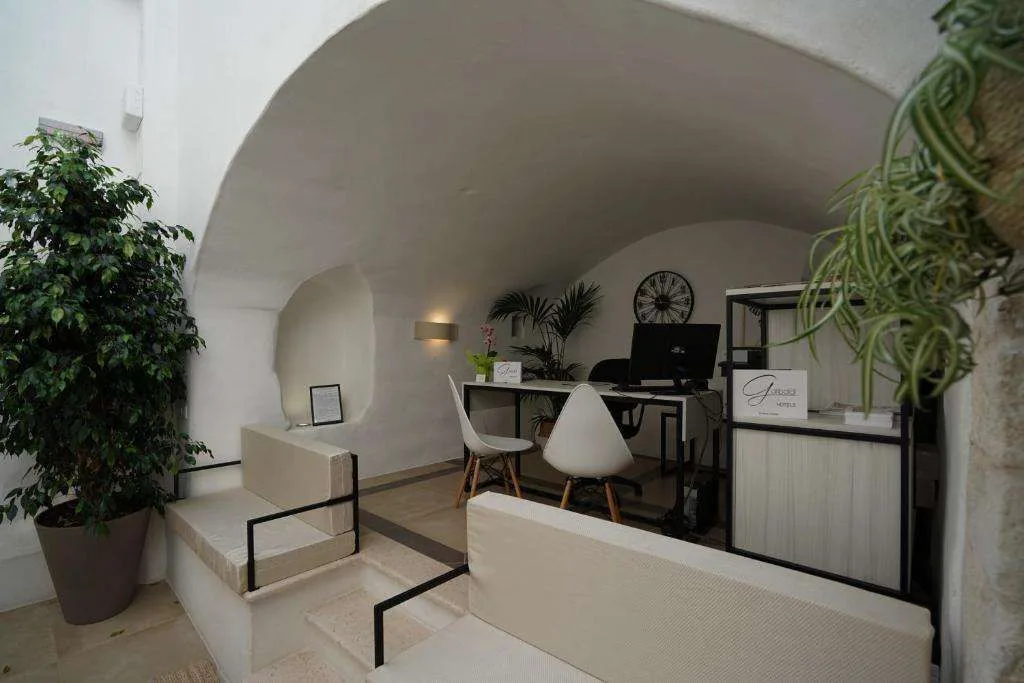Reception dell'hotel con scrivania, piante verdi e soffitto a volta bianco