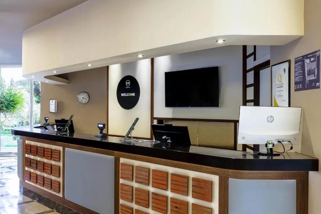Reception dell'hotel con bancone in legno e schermo di benvenuto