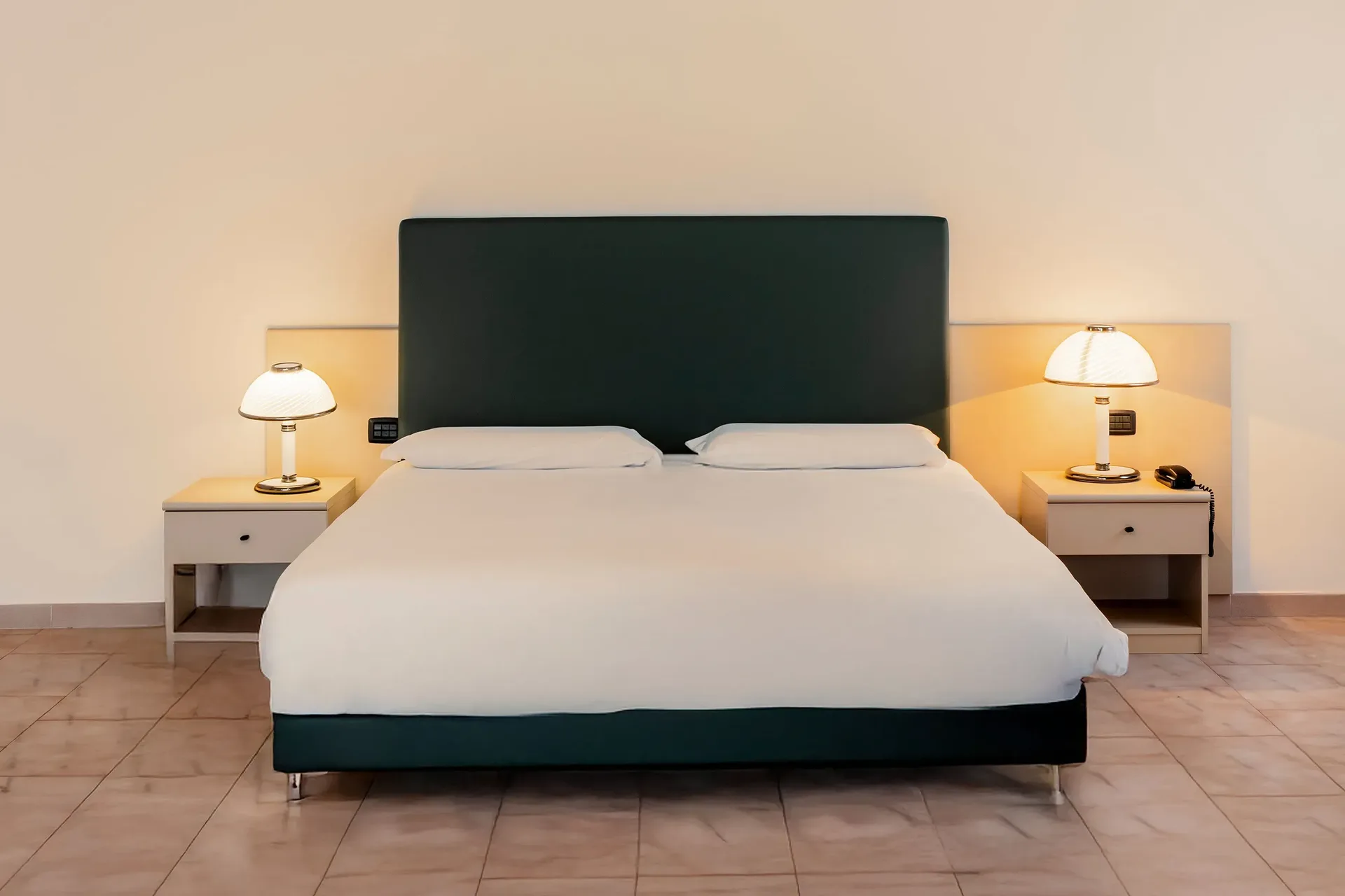 Camera con letto matrimoniale, testiera verde e lampade da comodino