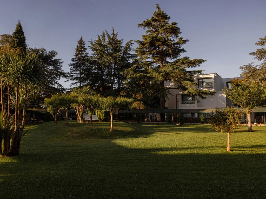Edificio bianco dell'hotel immerso tra alberi e ampio prato verde