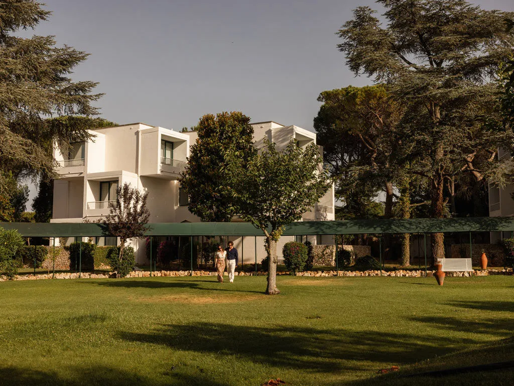 Coppia passeggia nel giardino davanti all'edificio bianco dell'hotel
