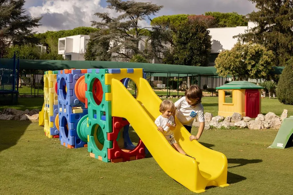Bambini giocano su scivolo giallo nell'area giochi del giardino