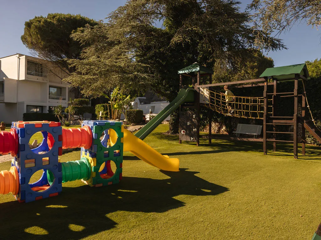 Parco giochi per bambini con scivoli e struttura colorata su prato verde