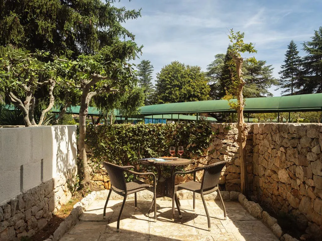 Terrazza privata con tavolo, sedie e calici di vino tra muretti in pietra