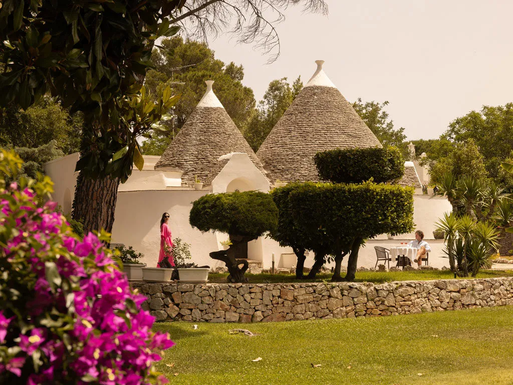 Trulli bianchi con tetti in pietra immersi nel giardino fiorito