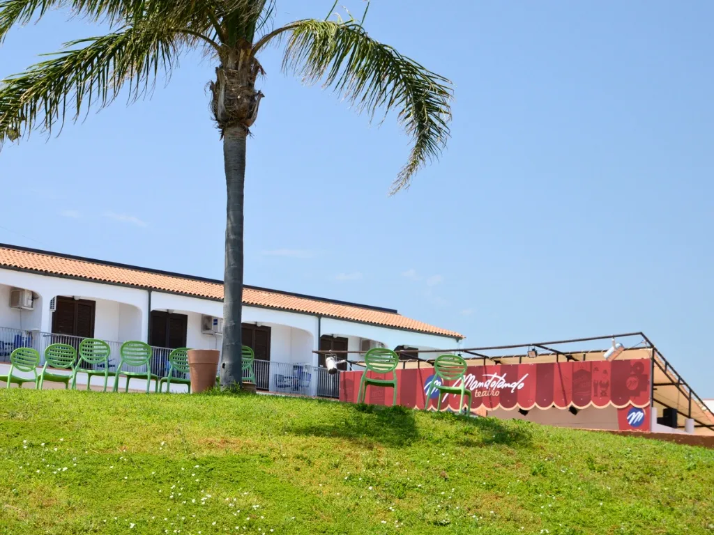 Edificio del villaggio con palma e teatro all'aperto sul prato