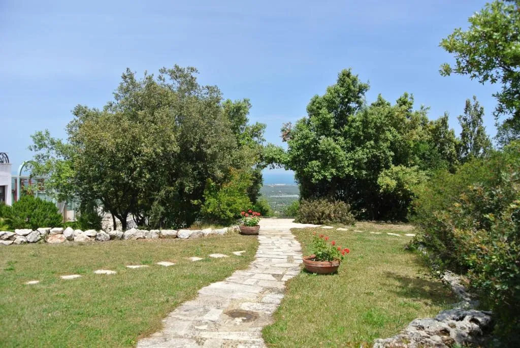 Giardino con vialetto in pietra, vasi di fiori e vista verso il mare