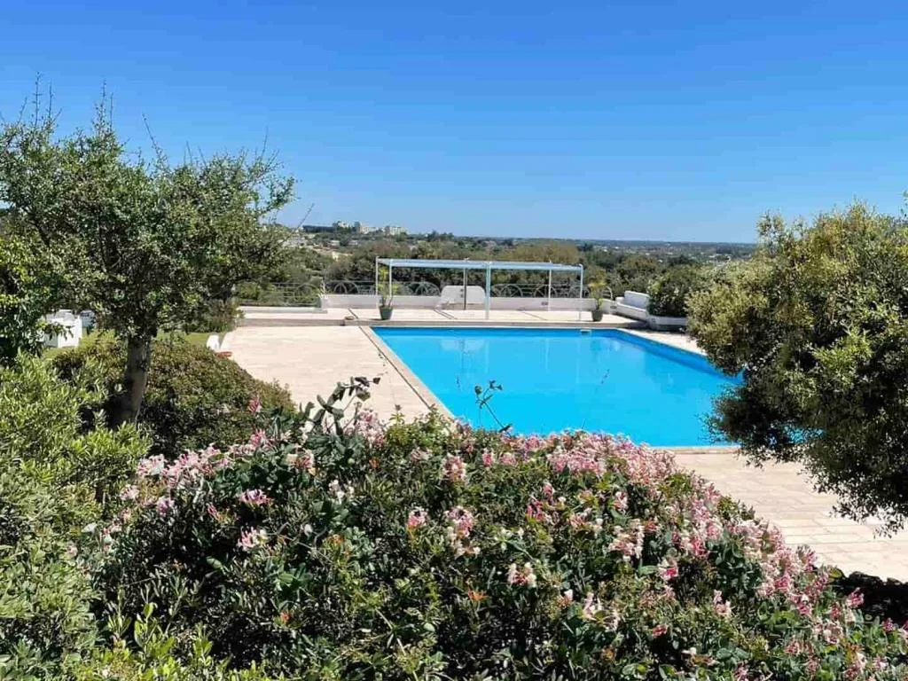 Piscina azzurra circondata da giardino fiorito con vista panoramica