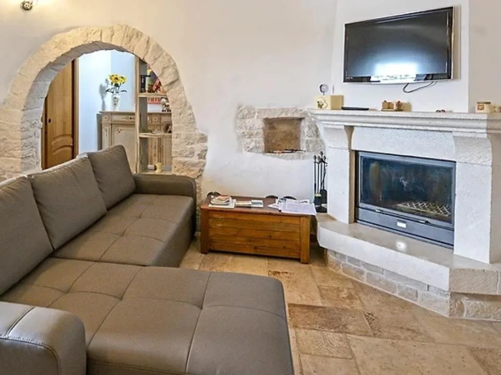 Salotto rustico con divano in pelle, camino in pietra e arco caratteristico