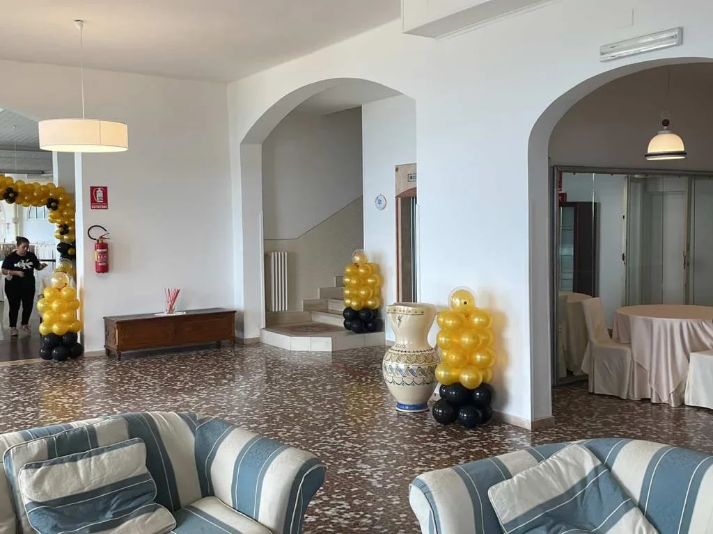 Hall con divani a righe, archi in pietra e decorazioni di palloncini