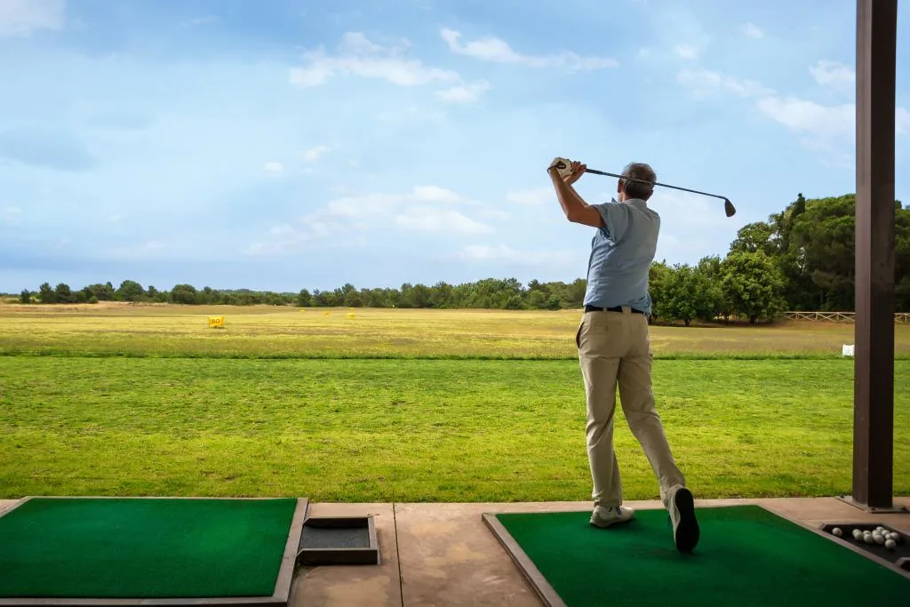 Golfista in azione al campo pratica circondato dal verde