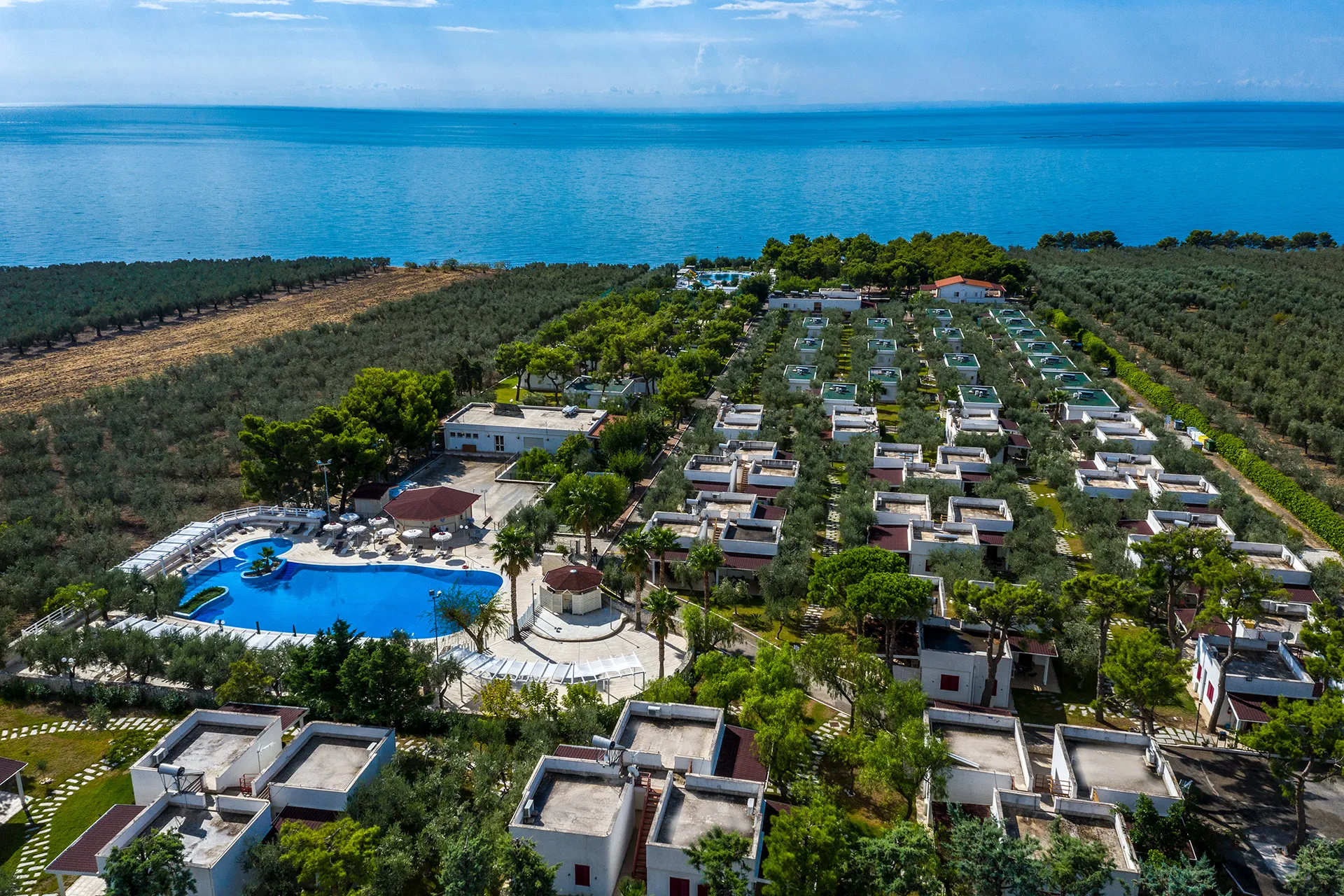 Panoramica aerea del villaggio con bungalow immersi nel verde e mare sullo sfondo