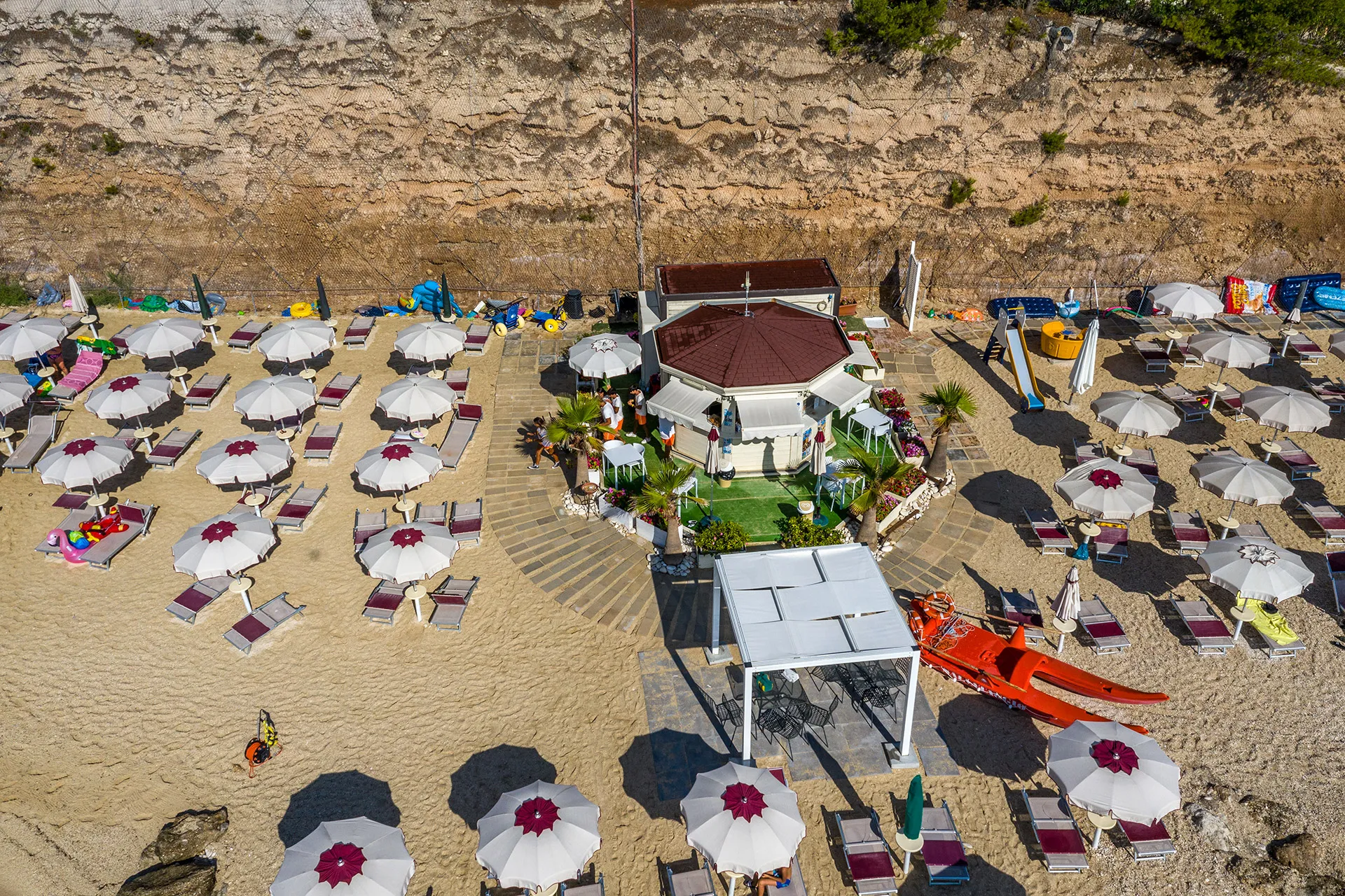 Stabilimento balneare con chiosco, ombrelloni e lettini sulla spiaggia sabbiosa
