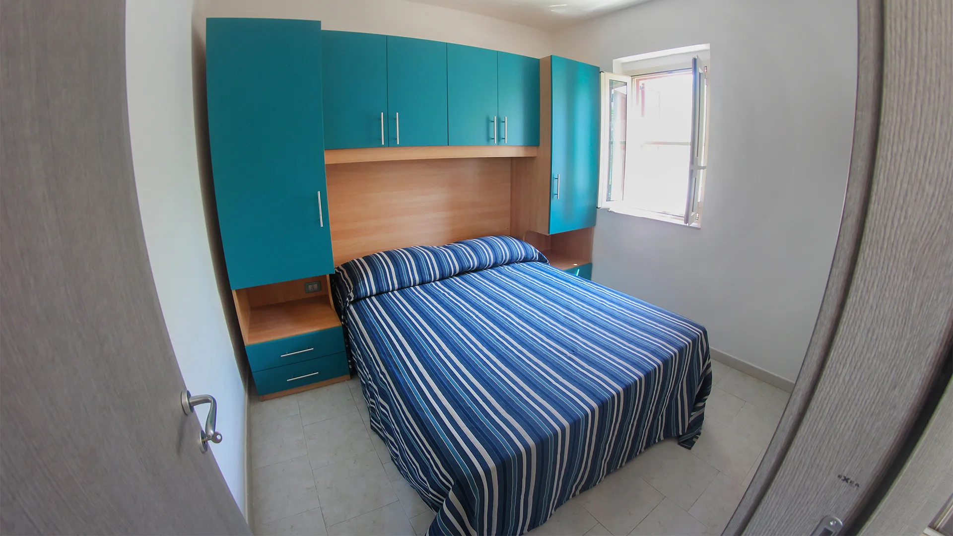 Camera da letto matrimoniale con armadio turchese e copriletto a righe blu