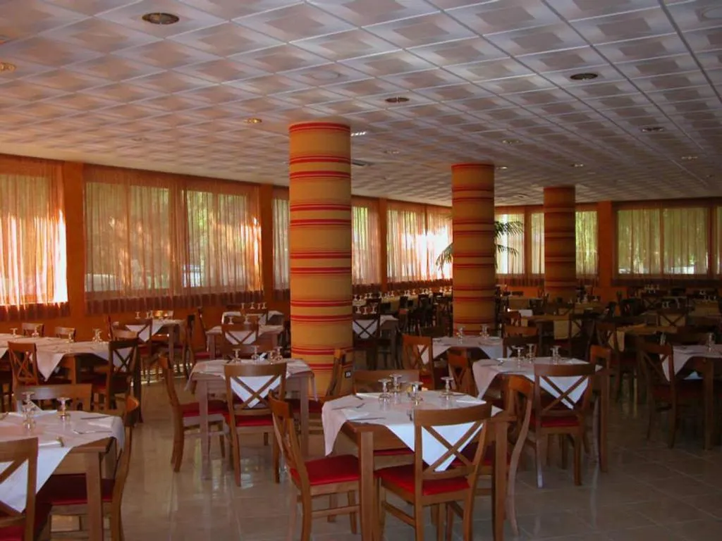 Sala ristorante interna con tavoli apparecchiati, colonne decorate e ampie vetrate