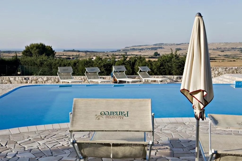 Bordo piscina con lettini, ombrellone e vista panoramica sulla campagna
