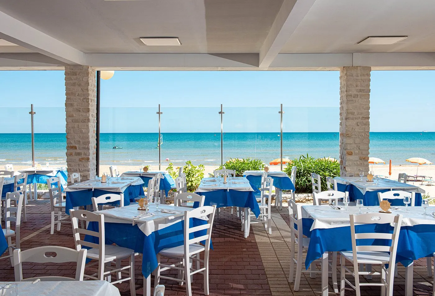 Ristorante fronte mare con tavoli e tovaglie blu e vista sulla spiaggia