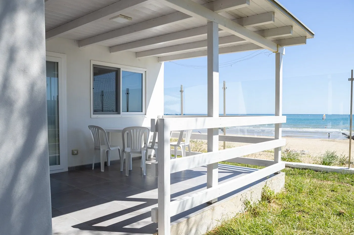 Veranda coperta con tavolo e sedie bianche e vista sul mare