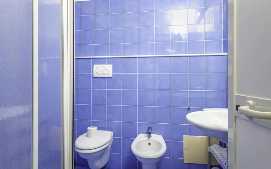 Bagno con piastrelle azzurre, doccia, WC, bidet e lavabo