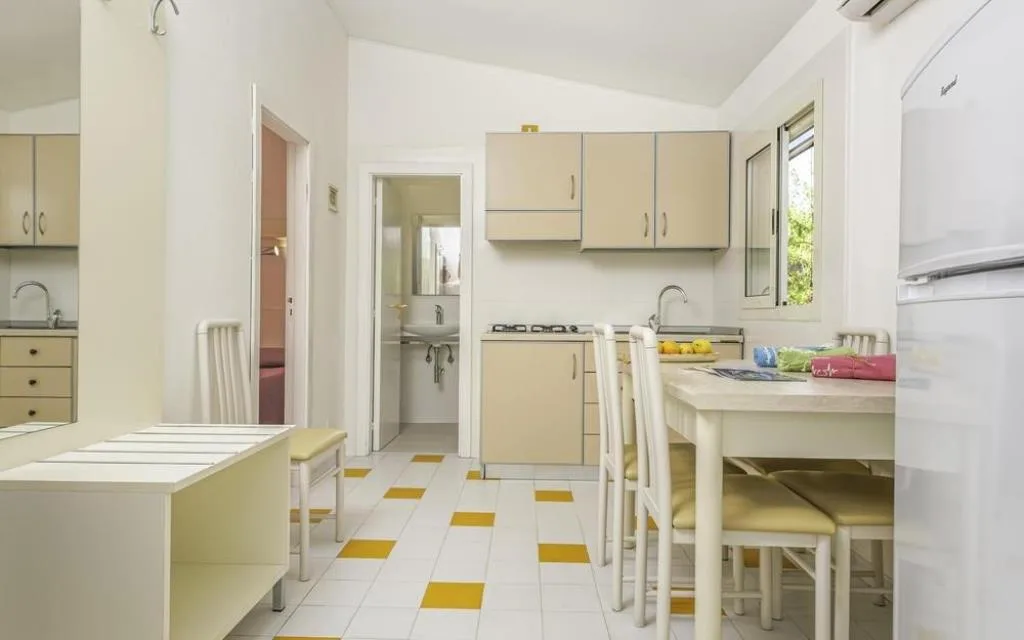 Cucina e zona pranzo con tavolo, sedie e angolo cottura