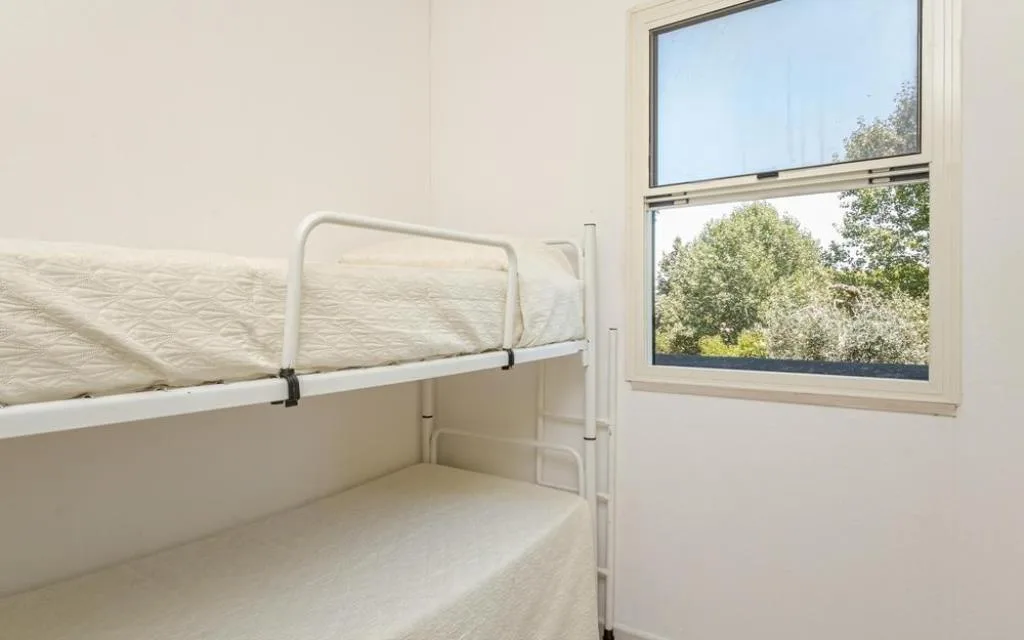 Camera con letto a castello bianco e finestra sul verde