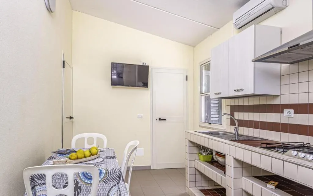 Cucina con angolo cottura, zona pranzo e TV a parete