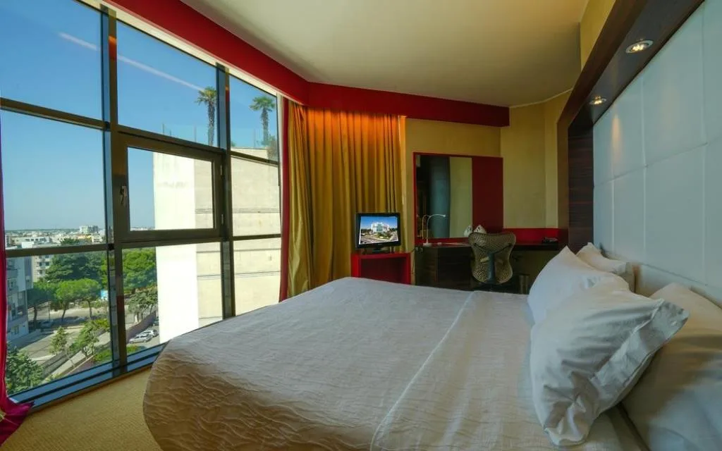 Camera con letto matrimoniale e grande vetrata con vista sulla città
