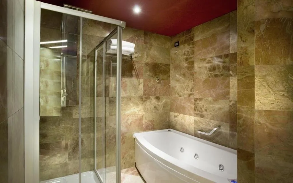 Bagno in marmo con doccia a vetri e vasca idromassaggio angolare