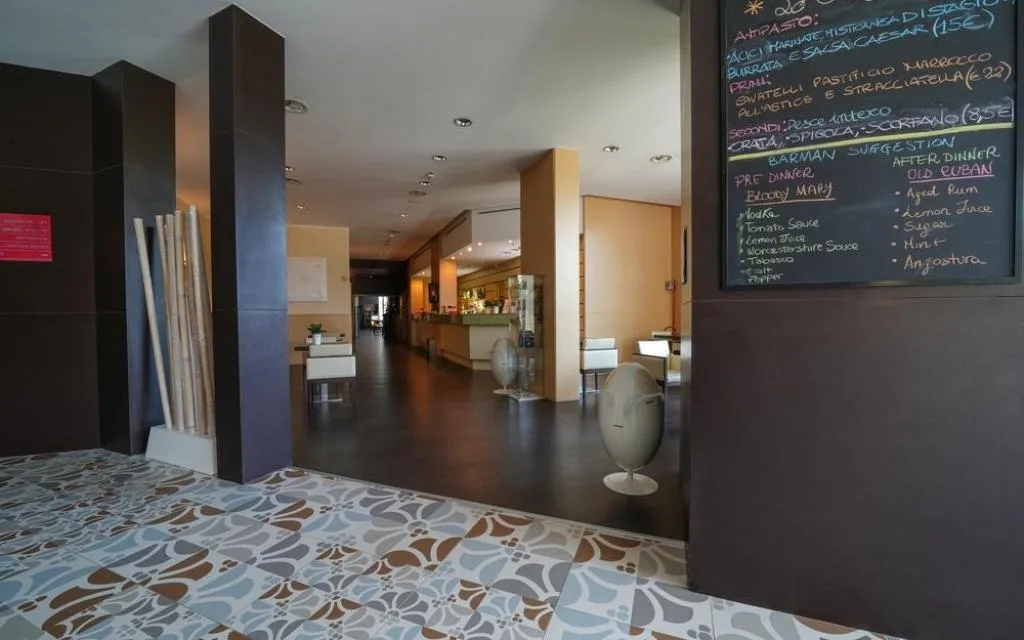 Ingresso e reception dell'hotel con lavagna del menu e pavimento decorato a mattonelle