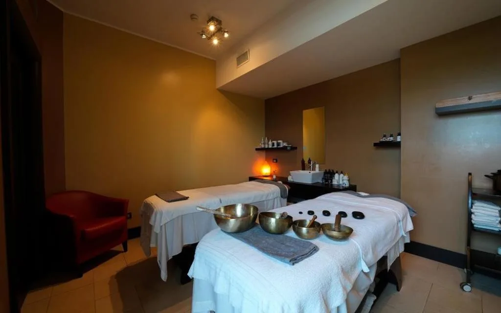 Sala massaggi con due lettini, campane tibetane e atmosfera rilassante