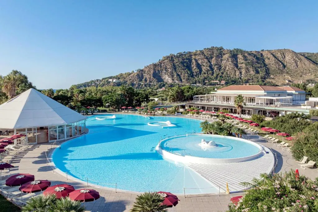 Vista panoramica della grande piscina del resort con montagne sullo sfondo