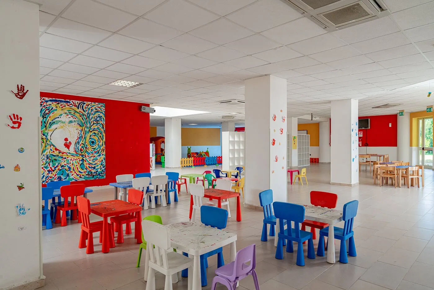 Sala interna miniclub per bambini con tavoli e sedie colorate